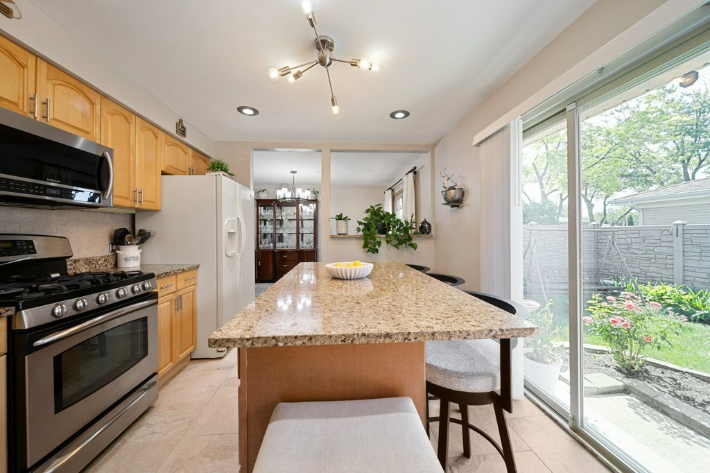 365 West Myrick Avenue Addison, IL 60101 - Photo 12 of 49 a kitchen with kitchen island granite countertop a stove a sink a refrigerator dining table and chairs a flat screen tv