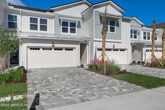 a view of a white house with large windows next to a yard
