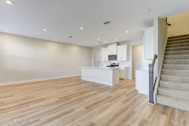 a view of a kitchen with wooden floor and electronic appliances