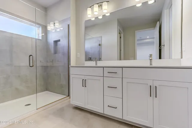 a bathroom with a sink a large mirror and shower