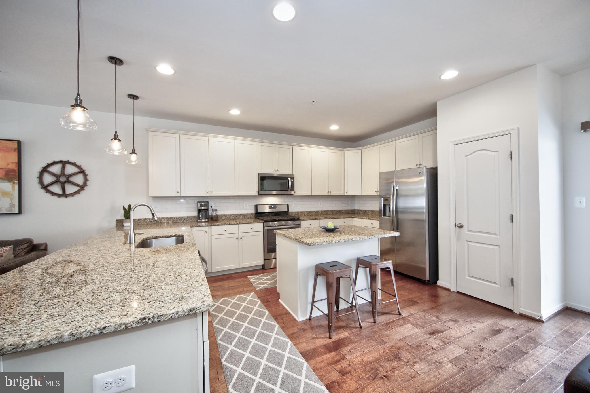 909 Morgan Run Road Baltimore, MD 21220 - Photo 12 of 41 a kitchen with stainless steel appliances granite countertop a sink dishwasher a refrigerator and white cabinets with wooden floor