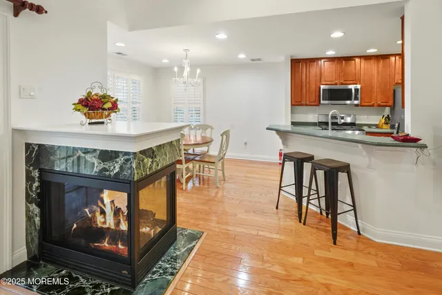 a kitchen with stainless steel appliances granite countertop a stove top oven a dining table and chairs with wooden floor