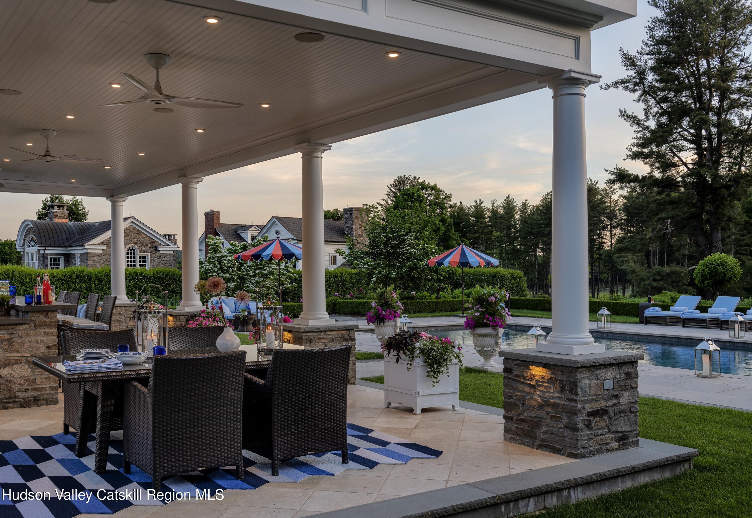 309 Woodstock Road Millbrook, NY 12545 - Photo 37 of 51 a view of a patio with table and chairs potted plants and palm tree