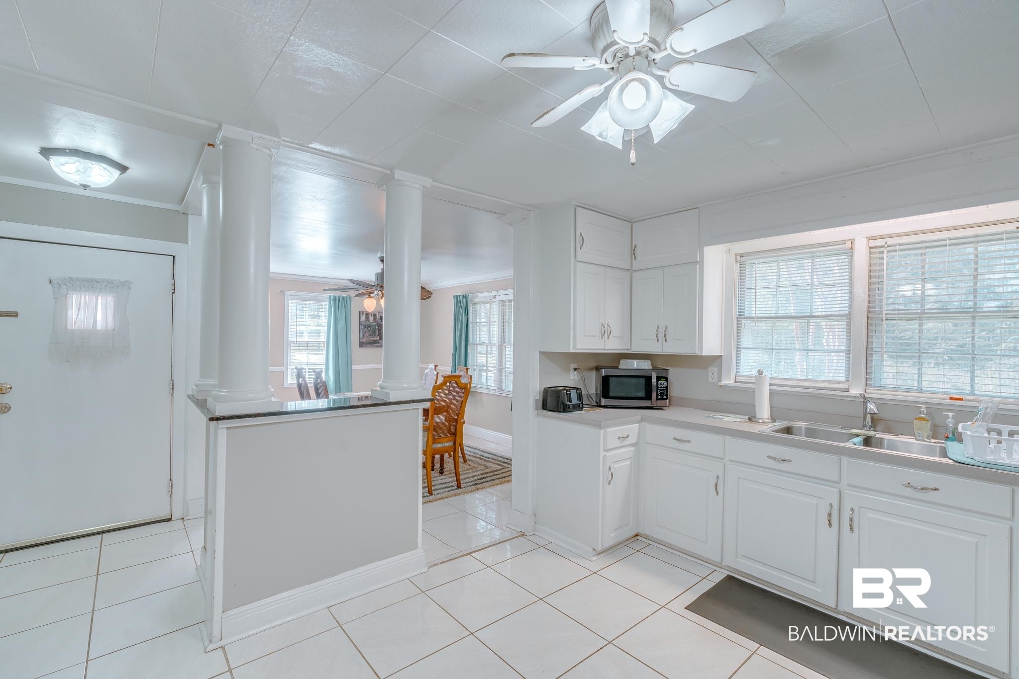 315 Fourth Avenue Chickasaw, AL 36611 - Photo 20 of 28 Kitchen with a ceiling fan, a wealth of natural light, stainless steel microwave, decorative columns, and white cabinets