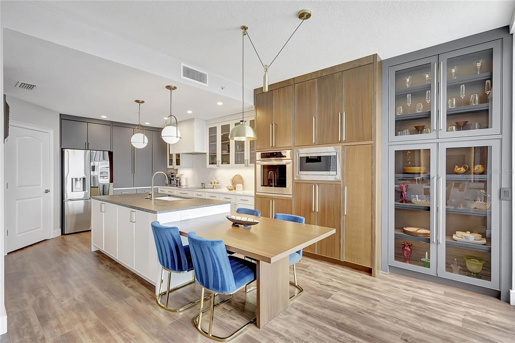610 Riviera Dunes Way, Unit 602 Palmetto, FL 34221 - Photo 21 of 79 a large kitchen with kitchen island a stove a refrigerator a sink dishwasher a dining table and chairs with wooden floor