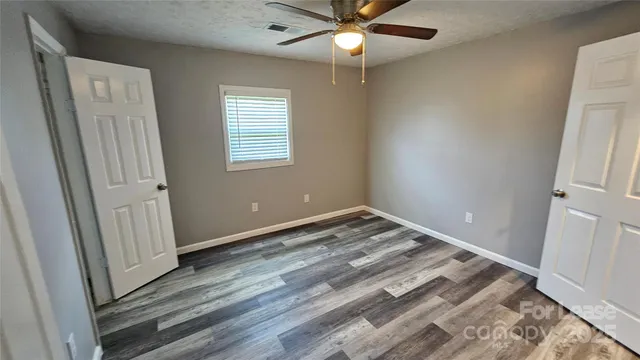 an empty room with closet and a chandelier fan