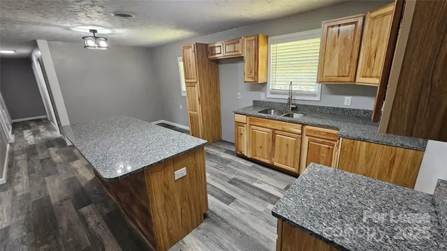 a kitchen with stainless steel appliances granite countertop a sink dishwasher a refrigerator and wooden floor
