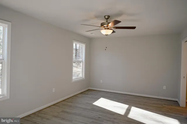a view of an empty room with wooden floor and window