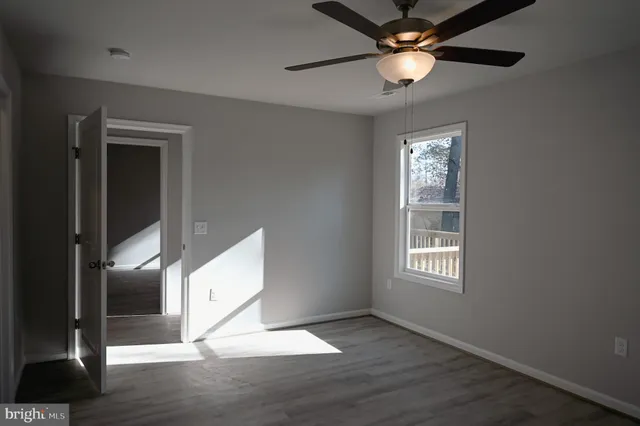 a view of an empty room with window and wooden floor