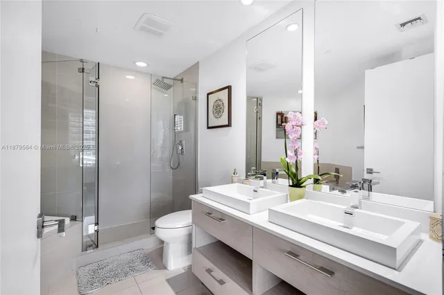 a bathroom with a double vanity sink toilet mirror and shower