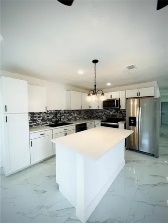 a large white kitchen with a refrigerator a stove a sink and a stove