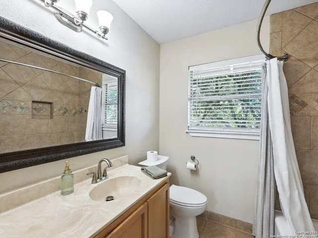 a bathroom with a sink vanity granite toilet and a mirror