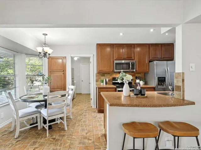 a kitchen with sink refrigerator dining table and chairs