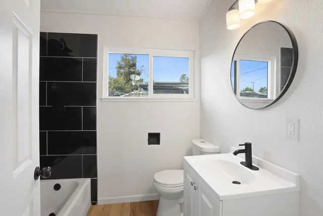 a bathroom with a sink a mirror a toilet and a window