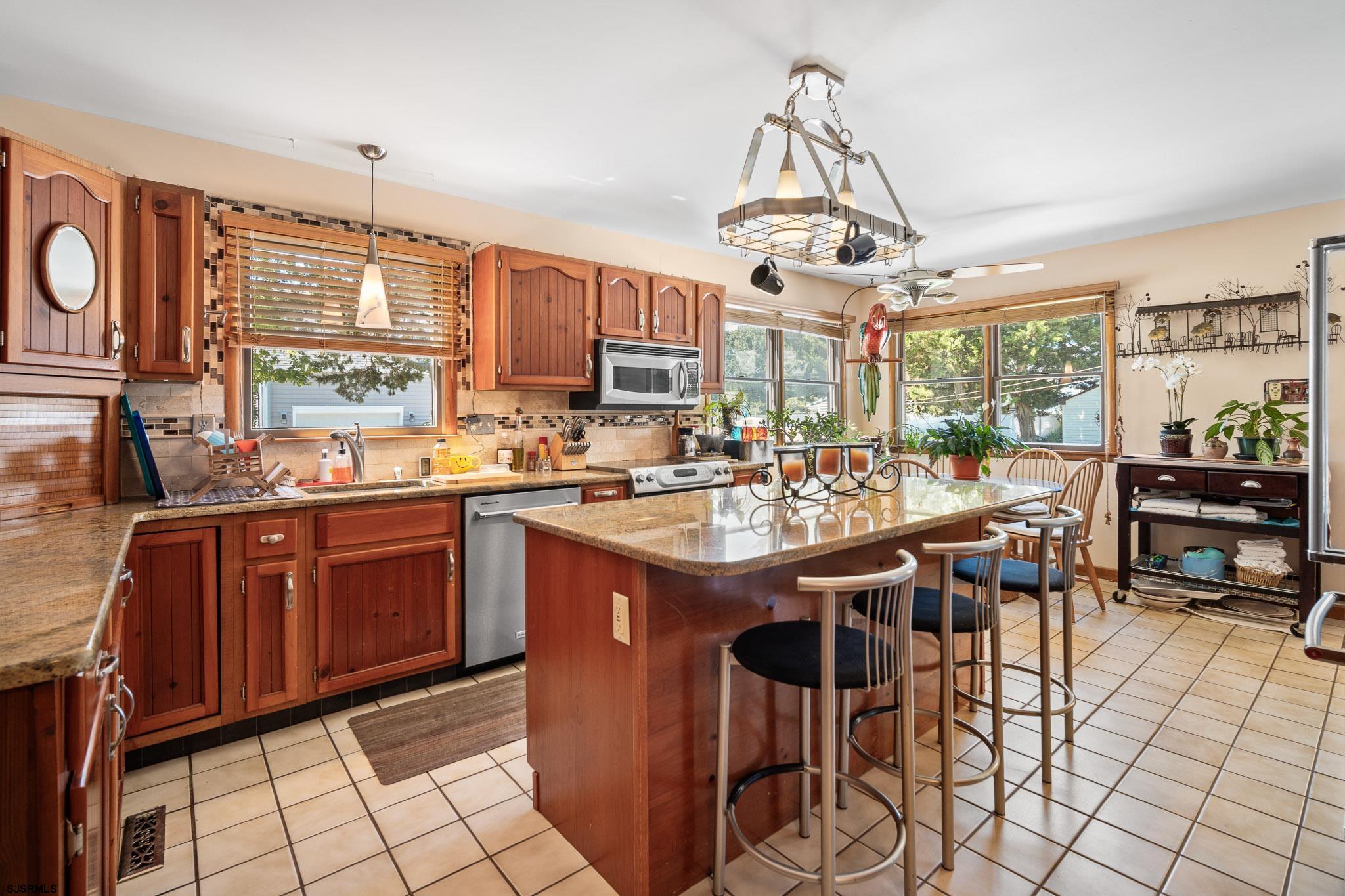 202 North Shore Road Marmora, NJ 08223 - Photo 15 of 31 a kitchen with stainless steel appliances granite countertop a stove top oven a dining table and chairs with the view of living room