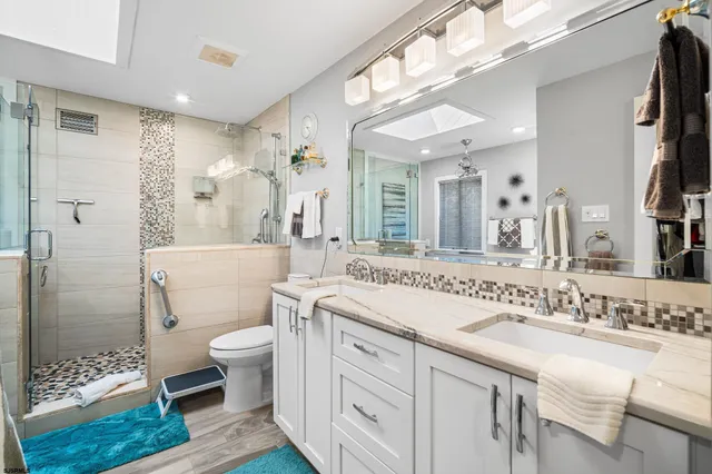 a spacious bathroom with a sink a toilet a mirror and shower