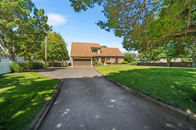 a view of a house with a big yard and large trees