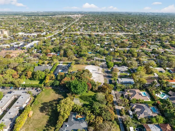 an aerial view of residential houses with outdoor space and trees