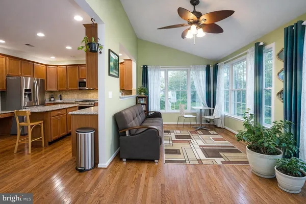 a living room with furniture dining table wooden floor and a large window