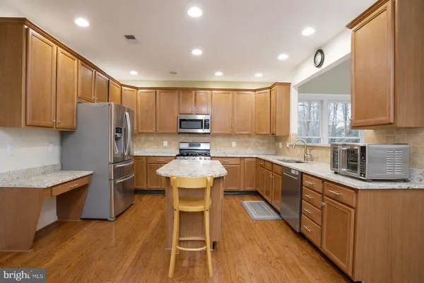 a kitchen with stainless steel appliances wooden floors wooden cabinets and sink