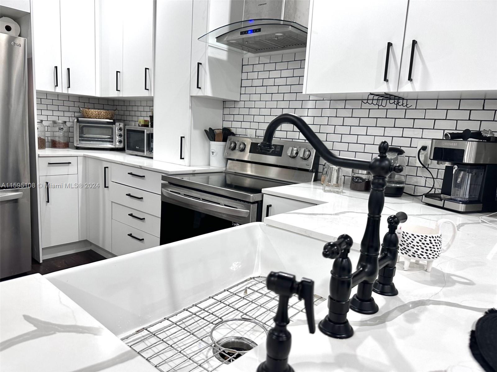 923 Southwest 13th Court Miami, FL 33135 - Photo 15 of 58 a kitchen with a sink a stove and a microwave