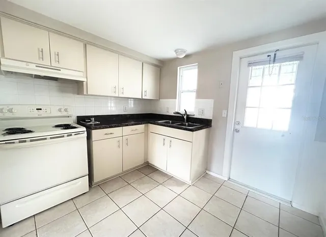a kitchen with white cabinets appliances a sink and a window