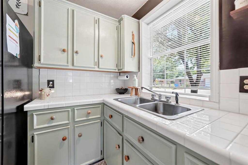 810 Edna Street Athens, TX 75751 - Photo 7 of 28 Kitchen featuring a double stainless steel sink with a window above, light green cabinetry, white tile countertops, and a white tile backsplash