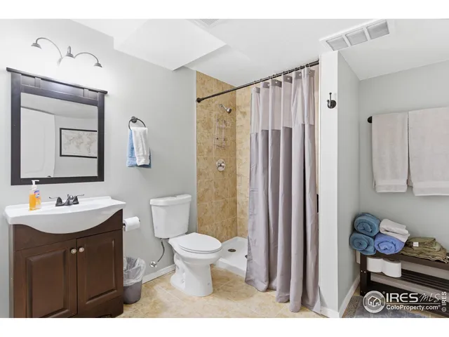 a bathroom with a toilet a sink a mirror a shower and vanity
