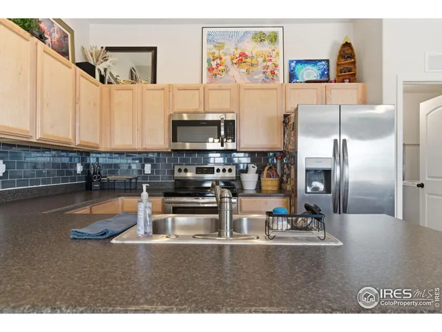 a kitchen with stainless steel appliances granite countertop a refrigerator a stove and a sink with wooden floor