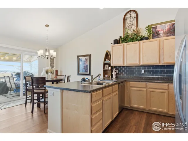 a kitchen with kitchen island granite countertop a stove a sink a dining table and chairs with wooden floor