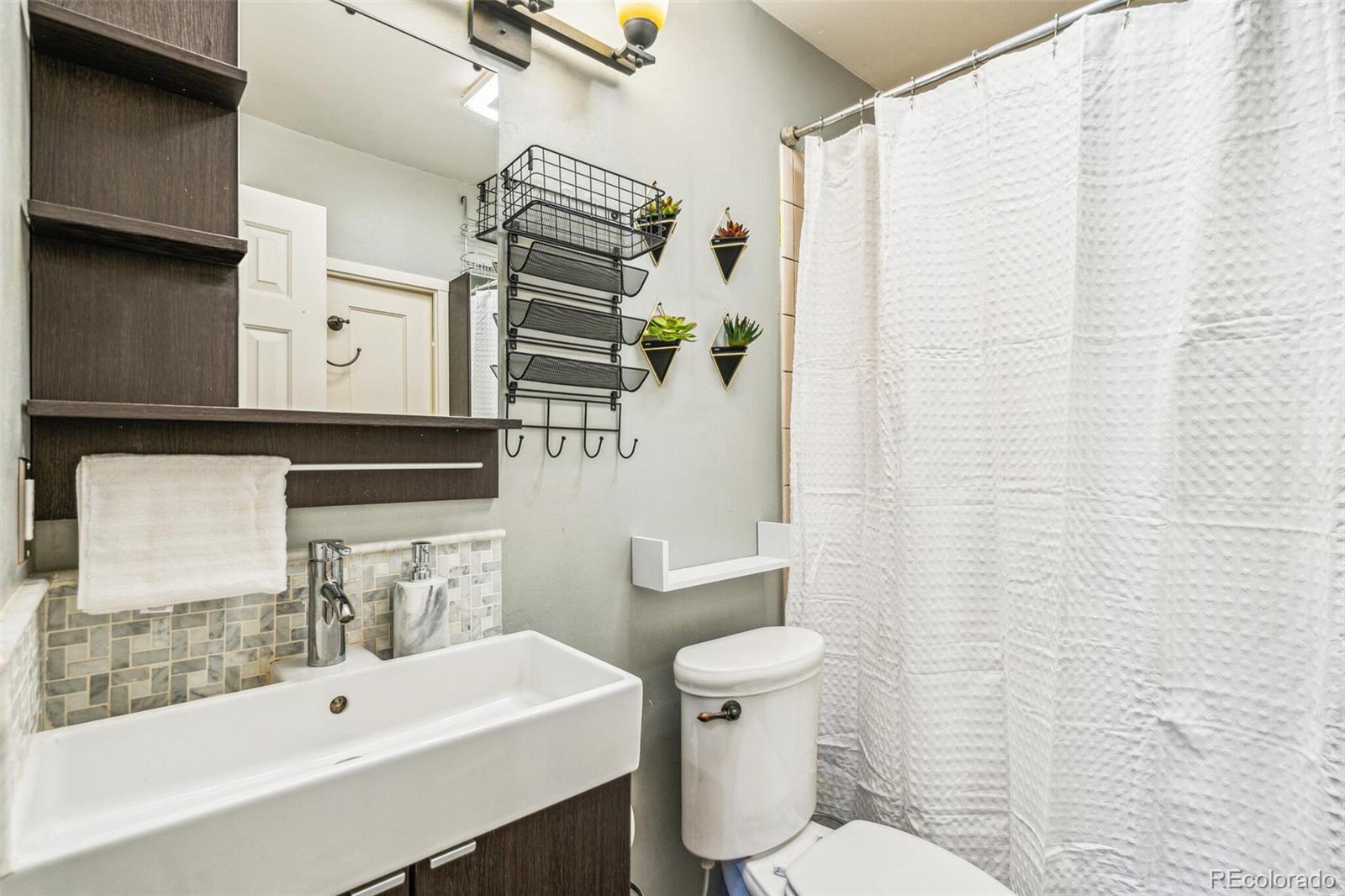 2963 Ames Street Wheat Ridge, CO 80214 - Photo 14 of 24 a bathroom with a sink a toilet and shower curtain