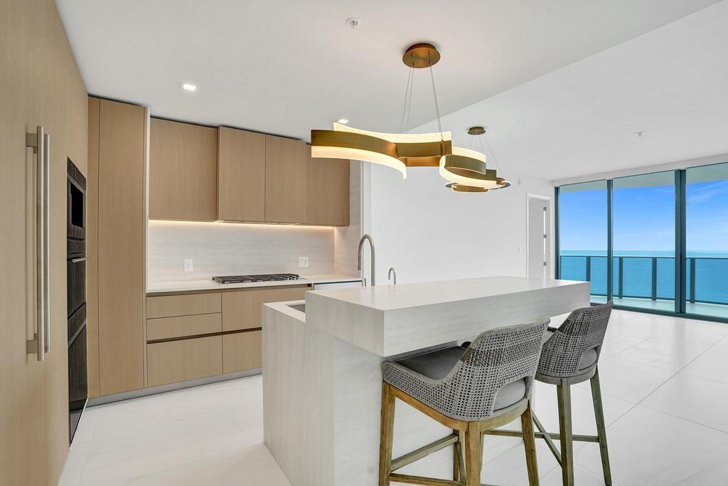 900 North Ocean Boulevard, Unit 1405 Pompano Beach, FL 33062 - Photo 13 of 67 a kitchen with a table chairs refrigerator and cabinets