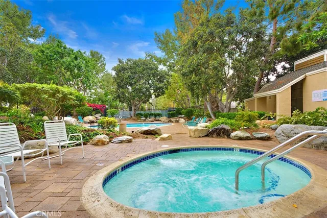 a view of swimming pool with lawn chairs and plants