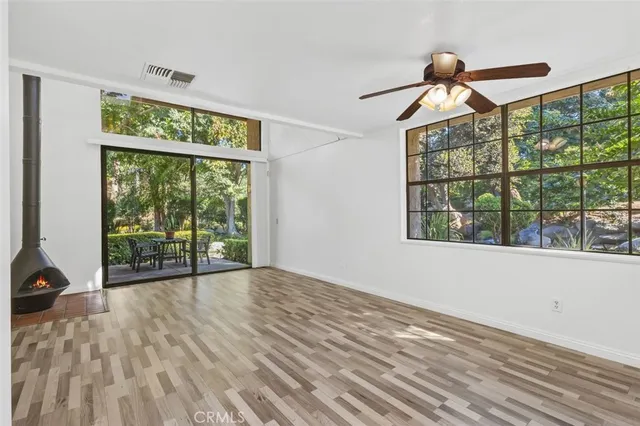 a view of empty room with wooden floor and fan