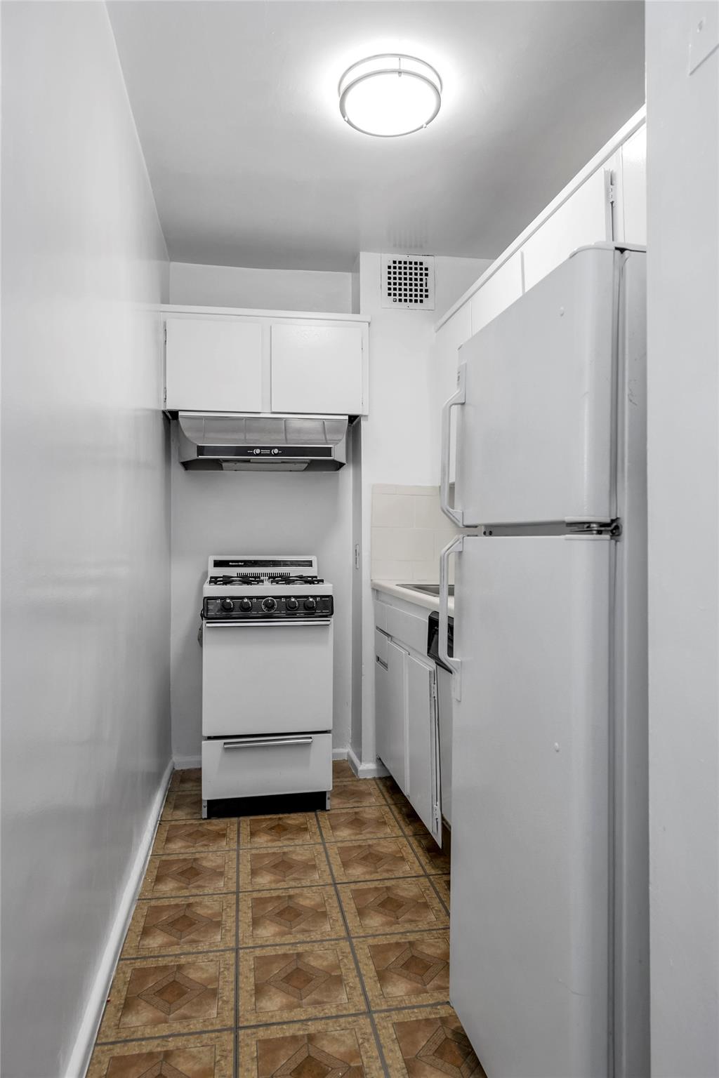 185 South Middle Neck Road, Unit 1G Great Neck, NY 11021 - Photo 4 of 9 Kitchen with white appliances and white cabinets