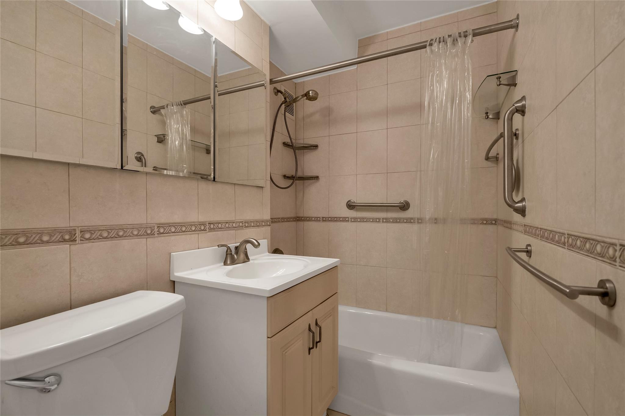 185 South Middle Neck Road, Unit 1G Great Neck, NY 11021 - Photo 7 of 9 Full bathroom with vanity, backsplash, tile walls, toilet, and shower / bath combo