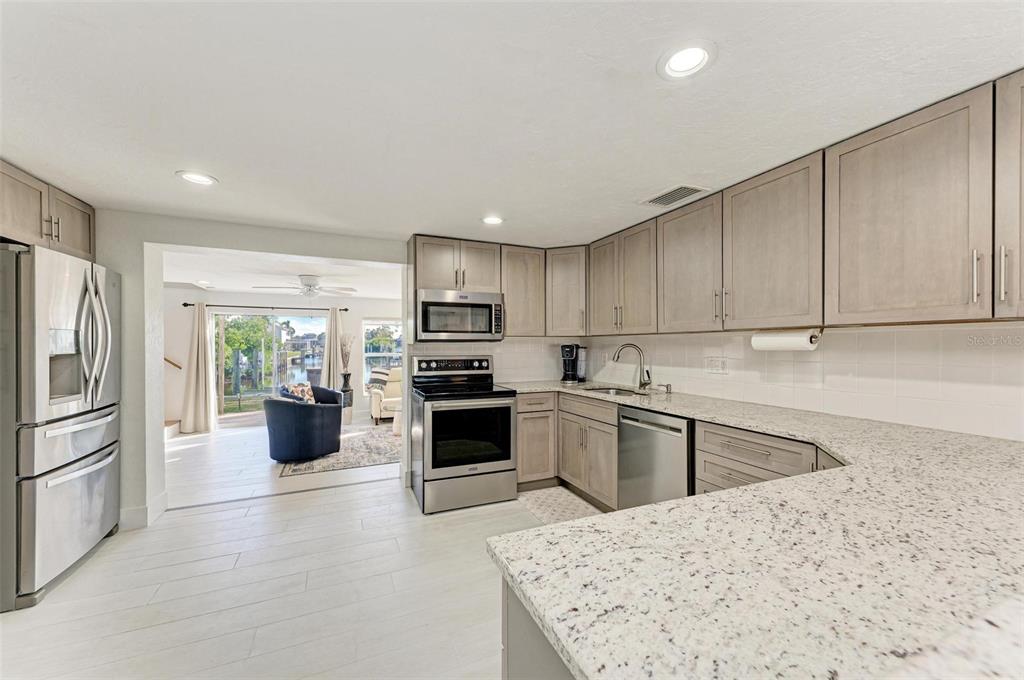 3311 Water Street Ellenton, FL 34222 - Photo 12 of 41 a kitchen with a refrigerator a stove top oven a sink dishwasher and white cabinets with wooden floor