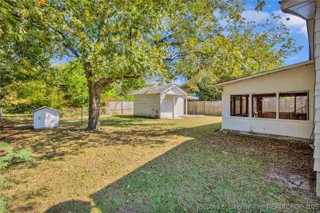 a view of small house with wooden fence and large trees
