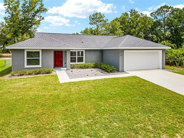 a front view of house with yard and trees in the background