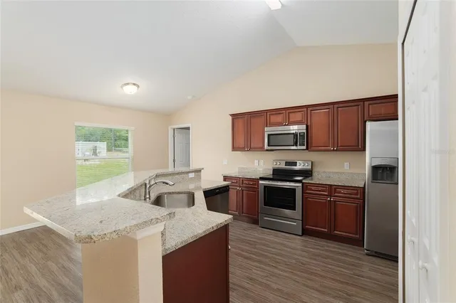 a kitchen with stainless steel appliances granite countertop a sink stove microwave and refrigerator