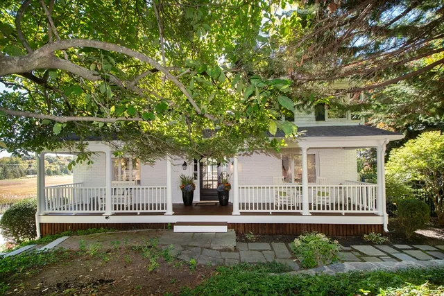 a view of a house with a small yard and a large tree