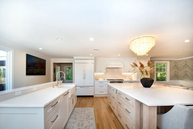 a large white kitchen with a large counter top sink and stainless steel appliances