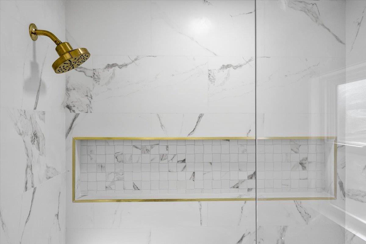 1676 Miller Farms Road Germantown, TN 38138 - Photo 26 of 37 Shower with large format white tile, gold-finish showerhead, recessed niche with mosaic tile inlay, and clear glass enclosure