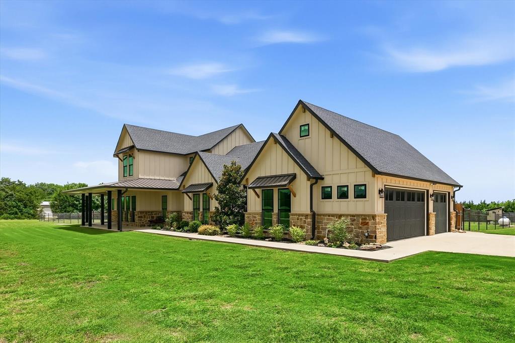 6020 Honeysuckle Road Midlothian, TX 76065 - Photo 2 of 39 Contemporary farmhouse-style exterior featuring board and batten siding, a stone veneer foundation, a covered front porch with dark columns, dark-framed windows, and a two-car garage with dark paneled doors