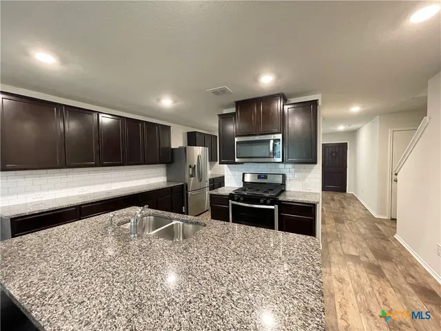 a large kitchen with kitchen island granite countertop a large counter top stainless steel appliances and cabinets