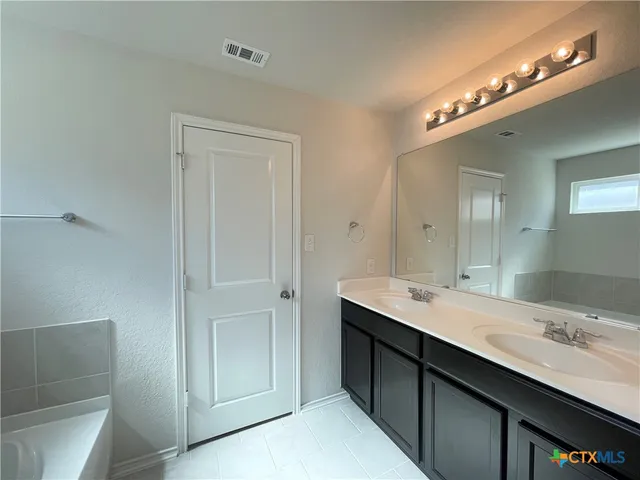 a bathroom with a double vanity sink a large mirror and a shower