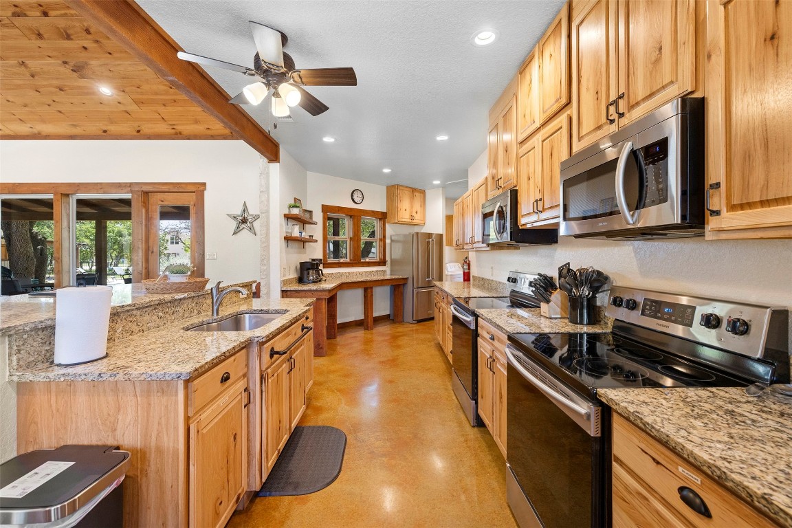 11 Stepping Stone Lane Concan, TX 78838 - Photo 14 of 47 a kitchen with stainless steel appliances granite countertop a sink a stove and a wooden cabinets