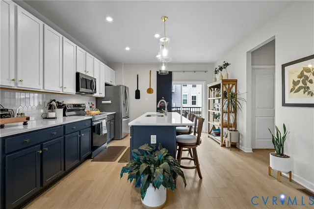 a kitchen with stainless steel appliances kitchen island granite countertop a refrigerator a stove a sink dishwasher and a dining table with wooden floor