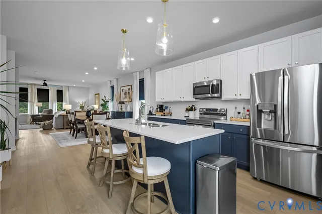 a kitchen with stainless steel appliances a refrigerator a stove a sink a table and chairs