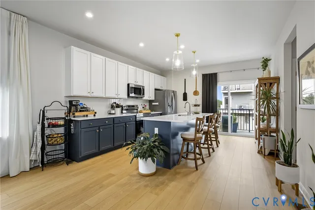 a kitchen with stainless steel appliances kitchen island granite countertop a refrigerator oven a sink dishwasher a dining table and chairs with wooden floor